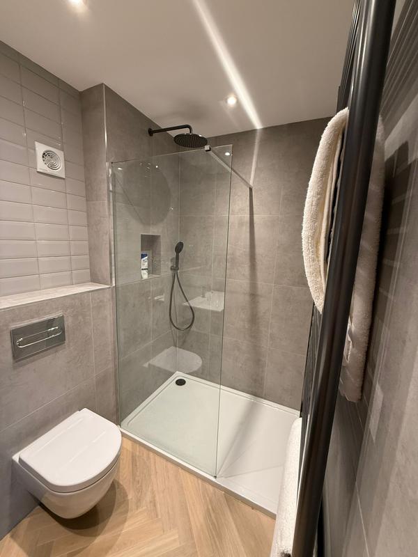 Walk-in shower with matt black fixtures and grey tile