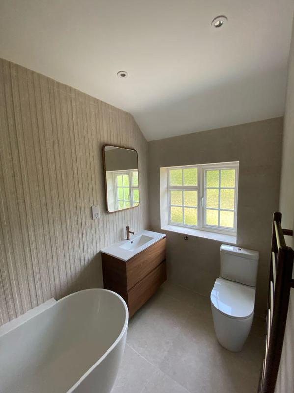 Small bathroom with freestanding bath and wood vanity
