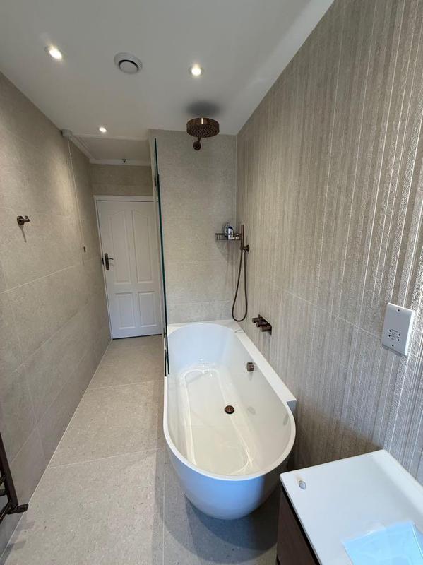 Freestanding tub in a soft-lit narrow bathroom